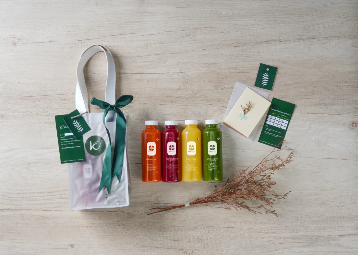 Hampers kecil Kboon: tas kain berpita hijau, botol jus, dan kartu ucapan